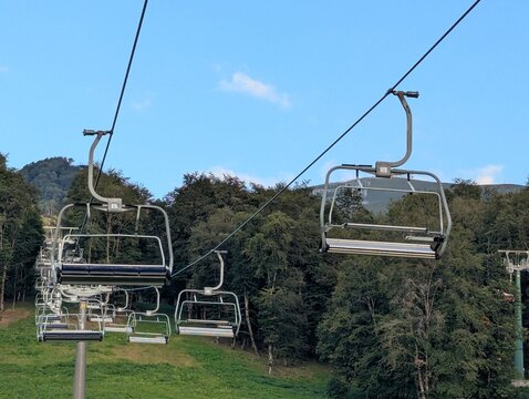 A ski lift drive station in summer, surrounded by lush greenery. Gears, wheels, and cables all exposed.
