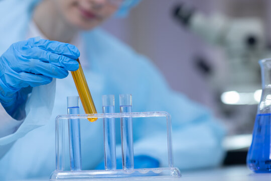 Scientist examines test tube with yellow liquid during scientific research. laboratory, testing, scientist, research, chemistry. Laboratory testing concept.