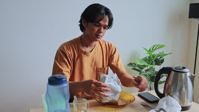 Young Man carefully unwrapping traditional packaged padang rice and using spoon to serve it onto plate at home 