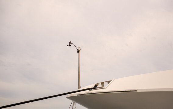Taut black mooring line on a white yacht hull with anemometer mast in the port of Rijeka, Croatia. Modern marina docking detail.