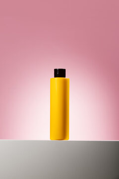 Yellow cosmetic bottle on pink background