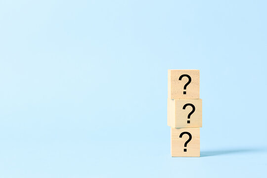 Three stacked wooden blocks with question marks on a blue background represent uncertainty, questions, problem solving, decision making, curiosity, confusion, inquiry, challenge, and seeking answers.