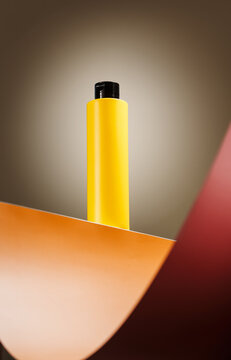 Yellow cosmetic bottle on warm geometric background