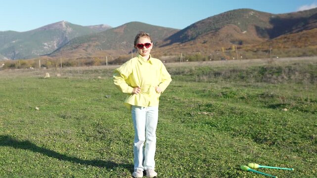 Girl, posing, mountains. Young girl posing in oversized yellow shirt and sunglasses outdoors with majestic mountains in the background.