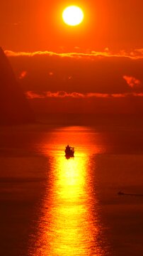 Sunset ocean boat silhouette of a small vessel crossing the suns golden reflection on a calm sea in a peaceful atmosphere