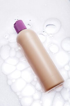Beige Cosmetic Bottle on White Foamy Surface
