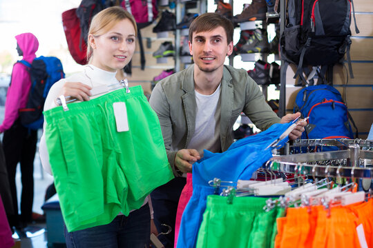 Married couple choosing summer shorts together in clothing store