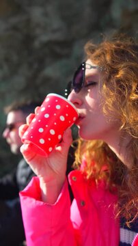 Woman coffee break enjoys a hot beverage from a red polka dot cup while relaxing outdoors on a sunny winter day