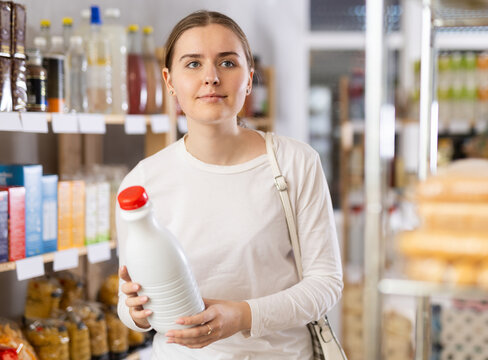 Young woman choosing milk in grocery store