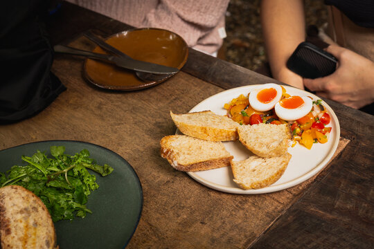 High angle shot of breakfast with soft boiled eggs, fresh tomato salsa and sourdough bread.