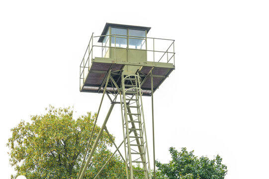 Military watchtower rises above green trees