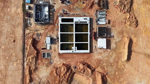 Aerial view of a construction site showcasing earthworks, soil excavation, and concrete foundation work in progress on a large industrial plot.