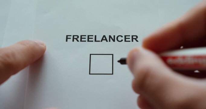 Hand marking the freelancer checkbox on a paper form, representing self-employment and independent work status.