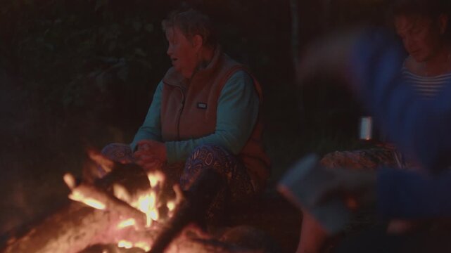 People sit in front of the bonfire burning in the wild area
