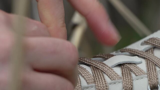 Shoelaces tying sneakers close up view of hands fastening white leather shoes during a morning walk or preparation
