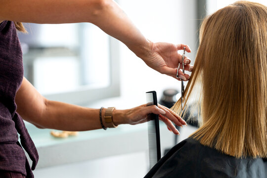 Professional hairstylist cutting client's blonde hair in a modern beauty salon