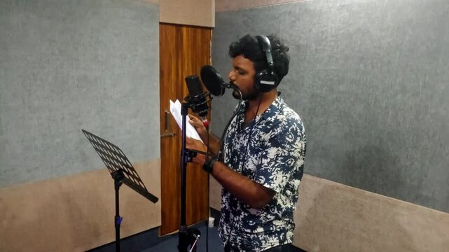 Voiceover Artist picking script paper from stand and delivering dialogues in Sound Recording Studio at hyderabad, telangana, india. internal shot, hand held shot, 4k.