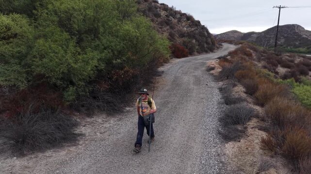 Close up aerial shot of a Man hiking in the hills of Temecula California. Aerial gimbal swings down from above to a nice frontal close up.