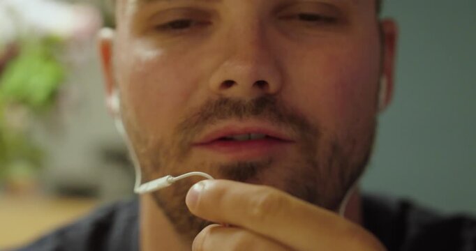 Close-up of a man holding an old-fashioned wired earphone microphone near his mouth for a call or voice communication.