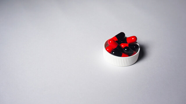 red and black capsules on top of bottle cap. Medication. 