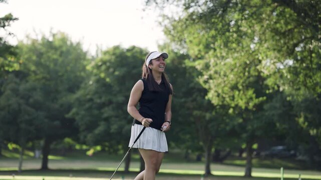Jubilant young woman golfer celebrating a successful putt on the green. She high fives her male friends in excitement on a sunny day