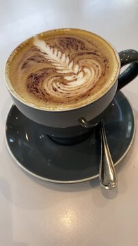 Hot cup of cappuccino coffee with beautiful latte art on cafe table 