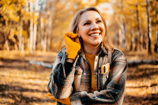 Joyful laughing woman in autumn woods with phone in pocket. Fall outdoor recreation and mental health digital detox concept. Enjoying pure solitude and seasonal nature away from internet.