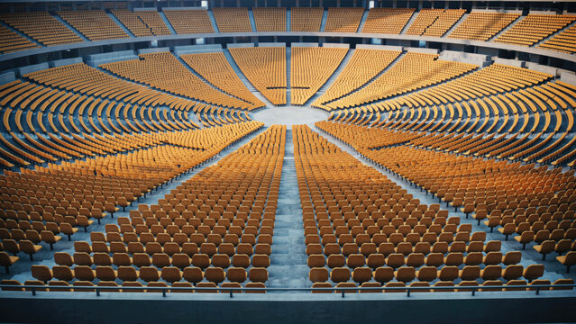 Empty stadium with rows of yellow seats arranged in a vast circular amphitheater layout with circular pattern surrounding surrounding central open arranged large auditorium