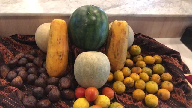 A vibrant assortment of fresh fruits and nuts displayed on a patterned cloth.