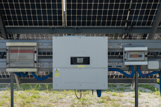 A solar inverter and circuit breaker boxes control current on a local farm. Photovoltaic distribution hardware converts renewable electricity. Modern equipment cuts property energy bills.