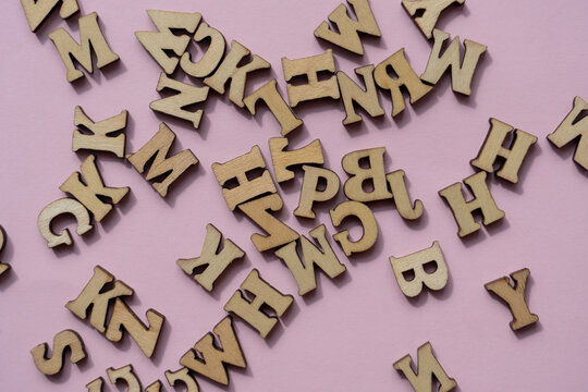 Background of scattered wooden letters on a light pink background.