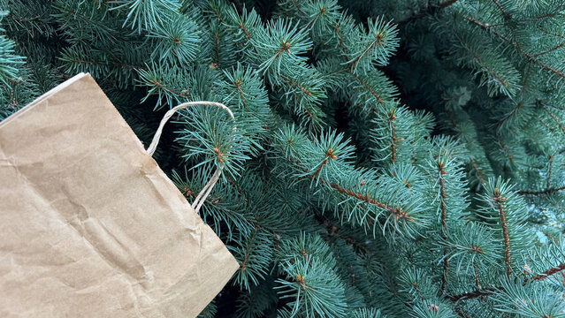 Close up of craft paper shopping bag on fir branch, eco friendly christmas delivery, sustainable lifestyle