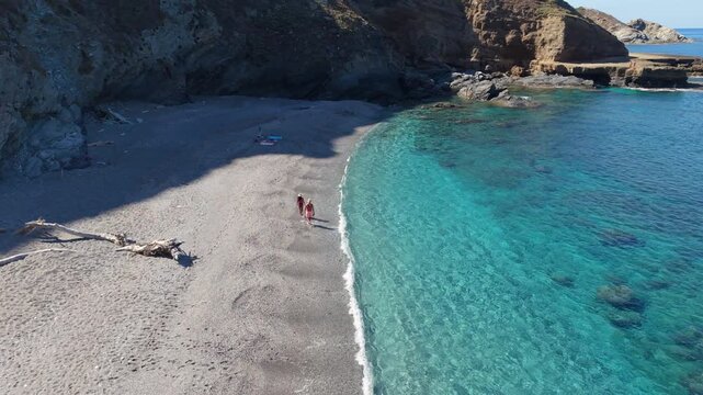 Experience the breathtaking beauty of La Frana Beach in Sardinia, Italy. The sandy shore and vibrant turquoise waters create a perfect setting for A diverse couple of Asian women and caucasian men 