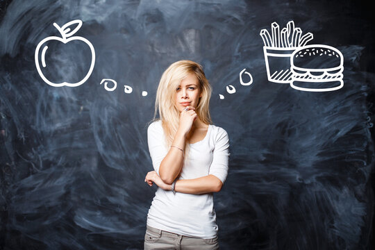 Woman makes a choice between bad food and healthy eating. Thoughtful blonde woman choosing. Concept of diet, nutrition choice, weight loss decision, and healthy lifestyle vs junk food.