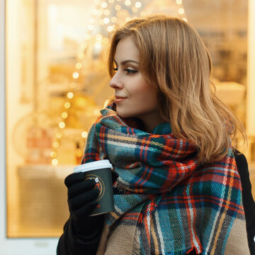 Close-up portrait of a sweet girl with a coffee on a background of lights