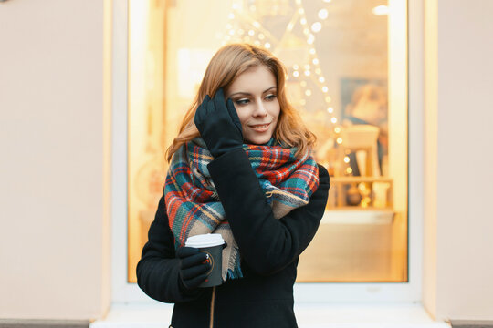 Beautiful young woman walks in the city and drinking coffee