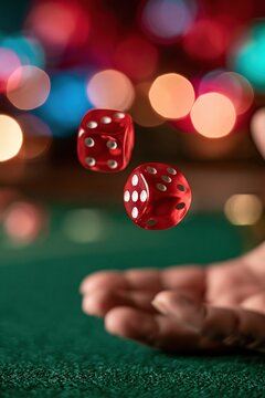 red dice tossed by hand on green felt