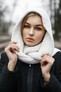 Stylish cute girl in a white knitted scarf on the background autumn park