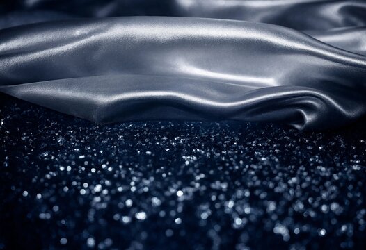 Abstract background featuring luxurious dark silver satin fabric flowing over a dark glittery surface