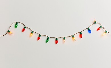 Obraz premium Colorful christmas light bulbs hanging against white background