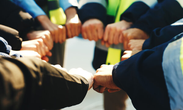 People, construction and meeting with fist bump in huddle for architecture development or mission. Group, contractor or team building with hands together, collaboration or unity for support or trust