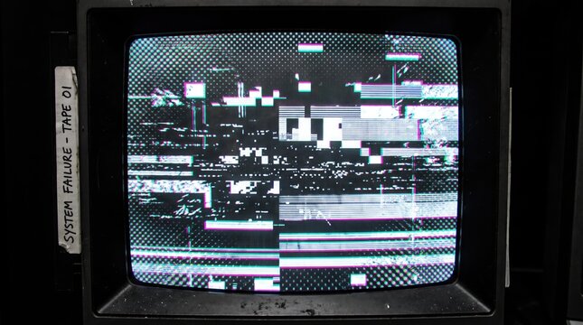 Old retro television screen showing digital signal glitch and static noise interference with a system failure label on the side