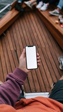 Hand holding blank smartphone on wooden boat deck