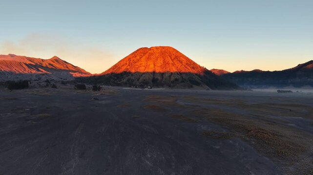 Mountain Batok glow red as dawn breaks. Smoke curls from earth silent breath