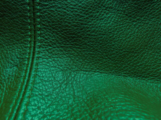 Fototapeta premium Texture dark emerald leather pattern, macro. Abstract deep green upholstery surface. Green leather texture with stitching. Dark green leather texture decorated with a seam. Horizontal photo.