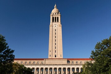 Obraz premium Tall university clock tower against clear blue sky