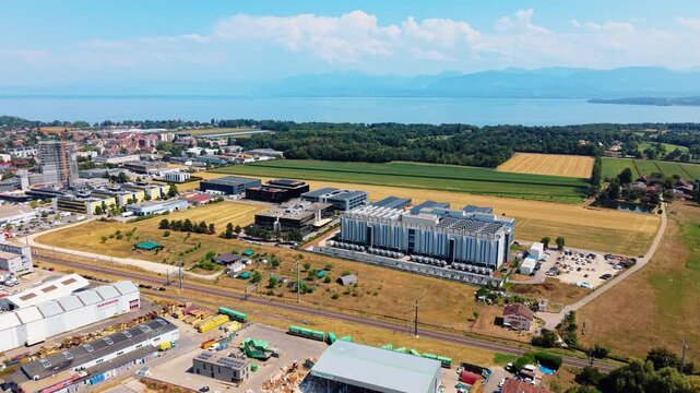 Drone advances forward above data center structure with lake behind it
