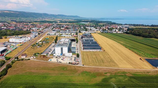 Drone approaches over golden field toward data center with lake behind