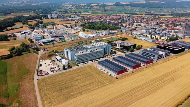 Drone pulls back above wheat field revealing distant data center complex
