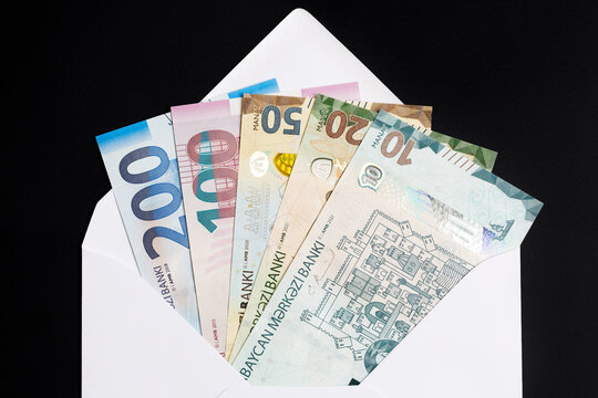 Azerbaijani manat in a white envelope on a black background